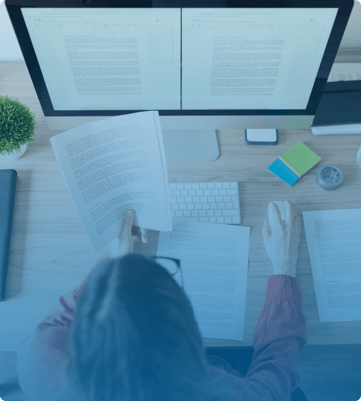 Content marketer analyzing documents and editing blog articles on dual screens for a SaaS content strategy