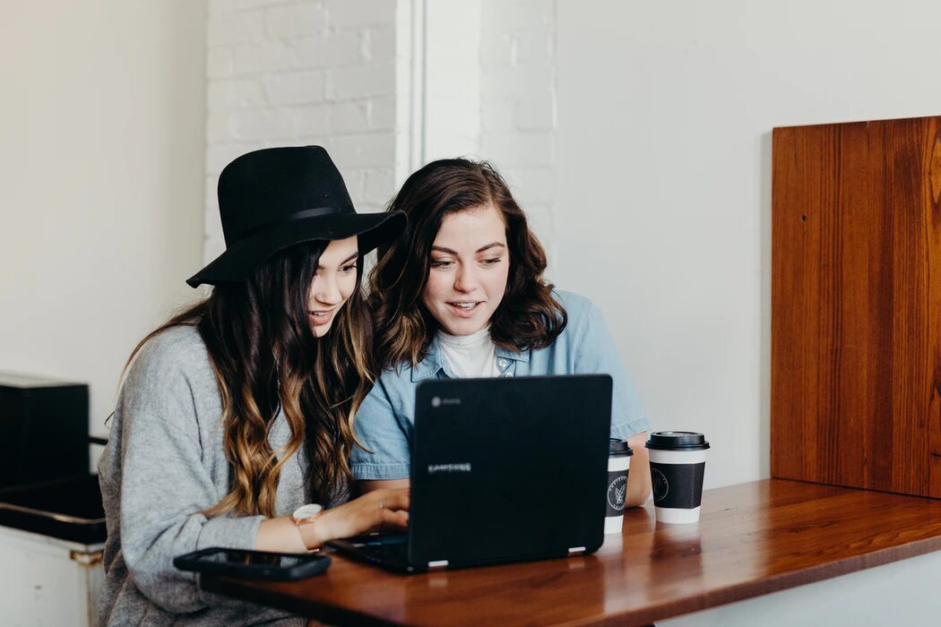 two people working on a laptop while smiling