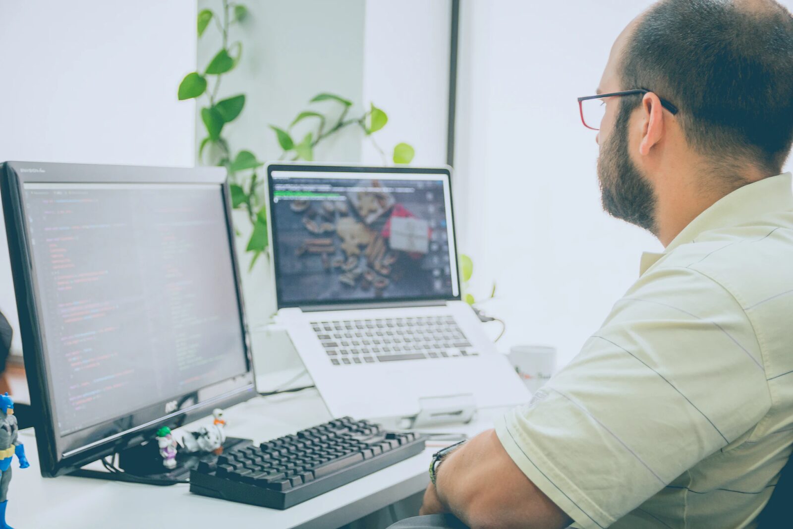 a person working with a monitor and a laptop on a desk