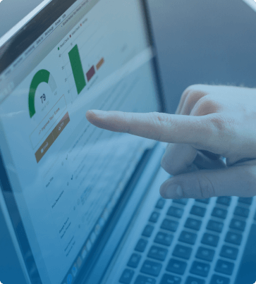 A person pointing at a laptop screen displaying data analytics, including graphs, metrics, and scores for performance evaluation