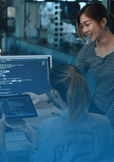 two women looking at code on a monitor