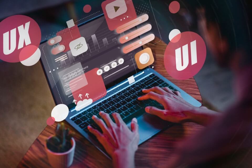 Person typing on laptop with floating UI/UX icons
