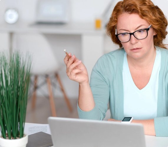 Woman holding a Pencil and looking at computer screen