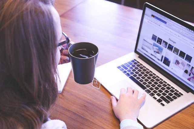 Woman looking at a laptop while drinking tea