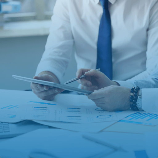 Two businessmen reviewing data on a tablet with documents and charts spread on the table