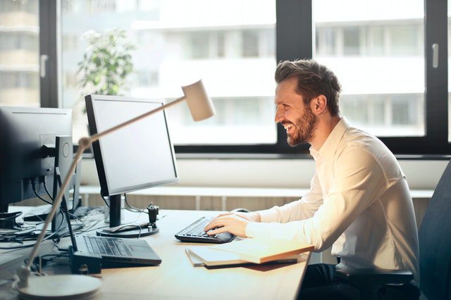 A smiling man working on a computer
