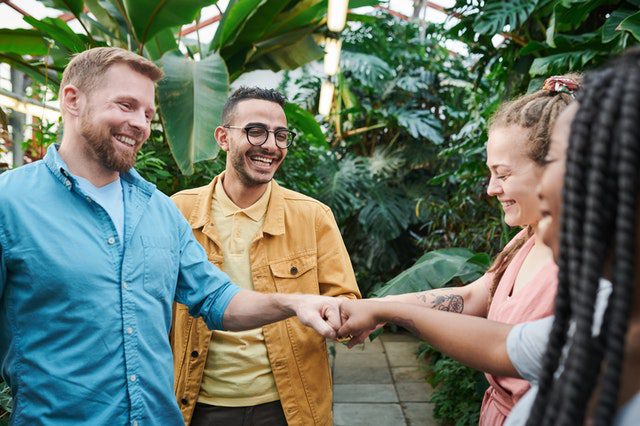 Four people smiling and fist bumping