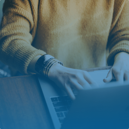 person with sweater typing on laptop