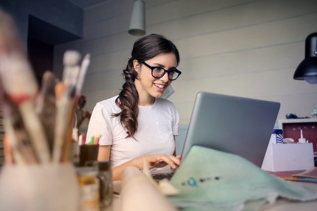A young woman smiling and using a laptop