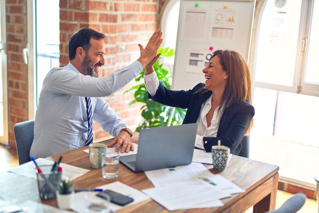 A man and a woman high-fiving in an office