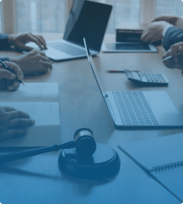 Legal SEO Image: A group of professionals working at a table with legal documents, laptops, and a judge's gavel in focus.