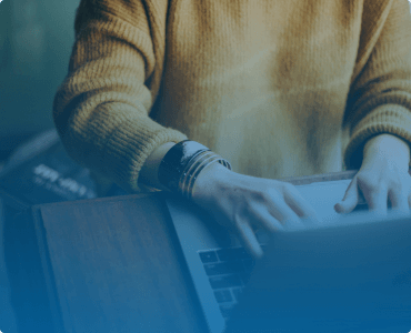 a person in a beige sweater typing on a laptop