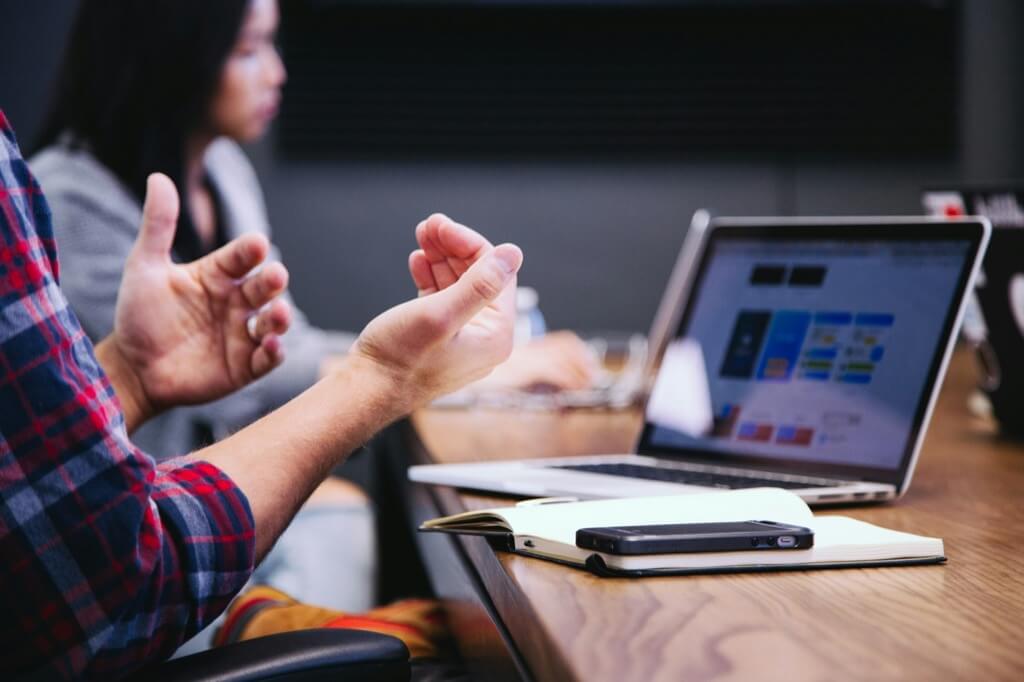 a person raising their hands in front of a laptop
