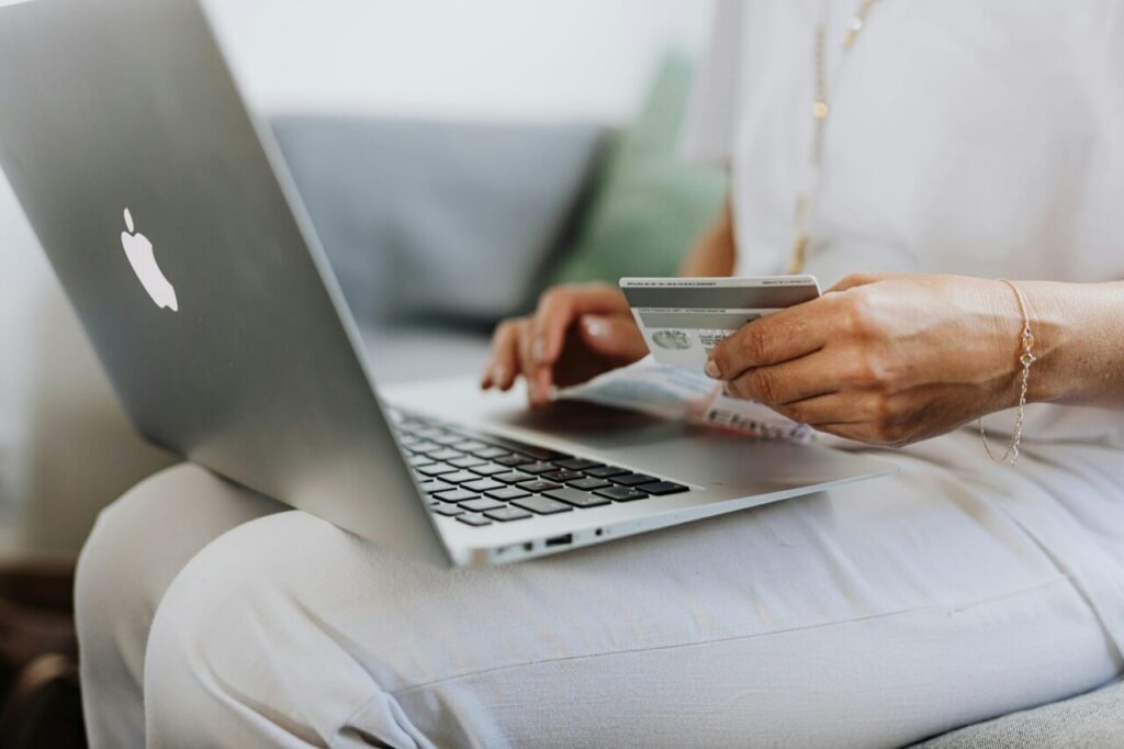 A person shopping on their laptop while holding a credit card