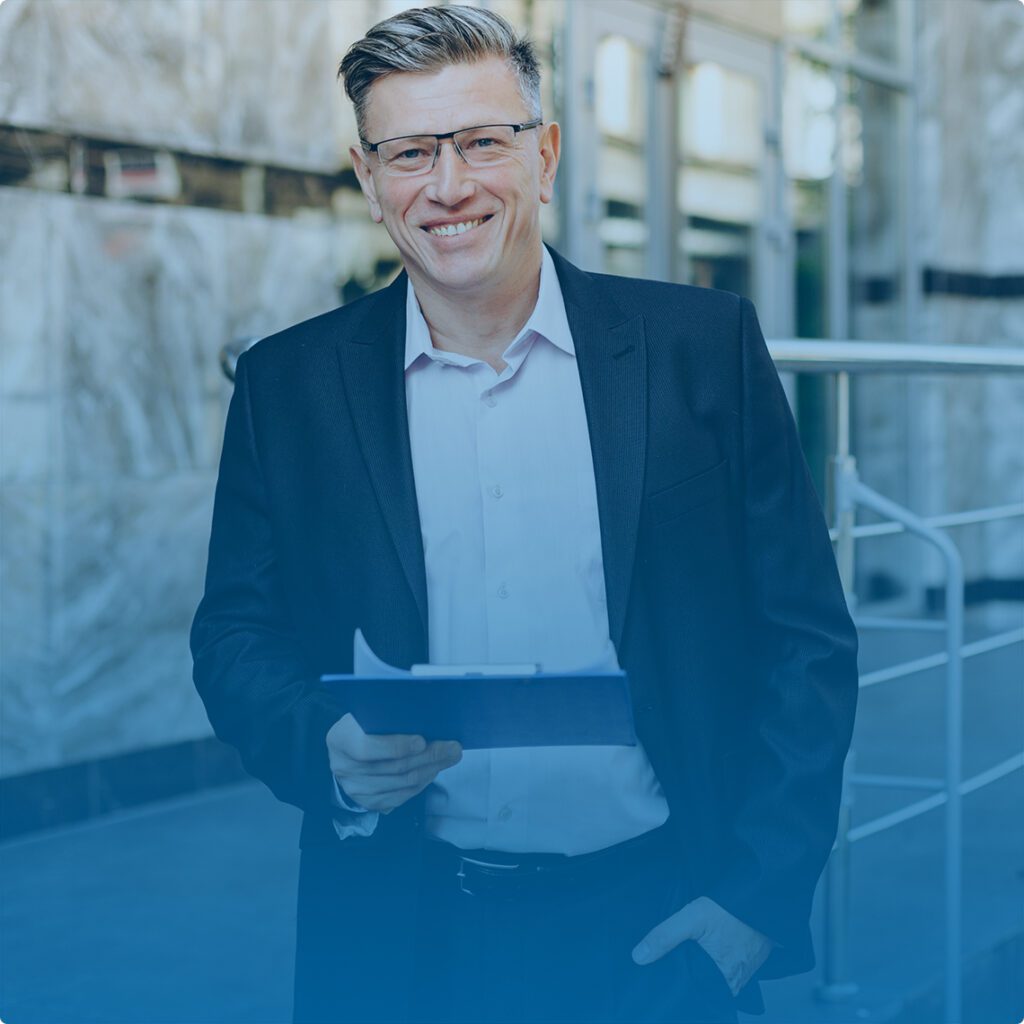 a smiling businessman with gray hair holding a tablet